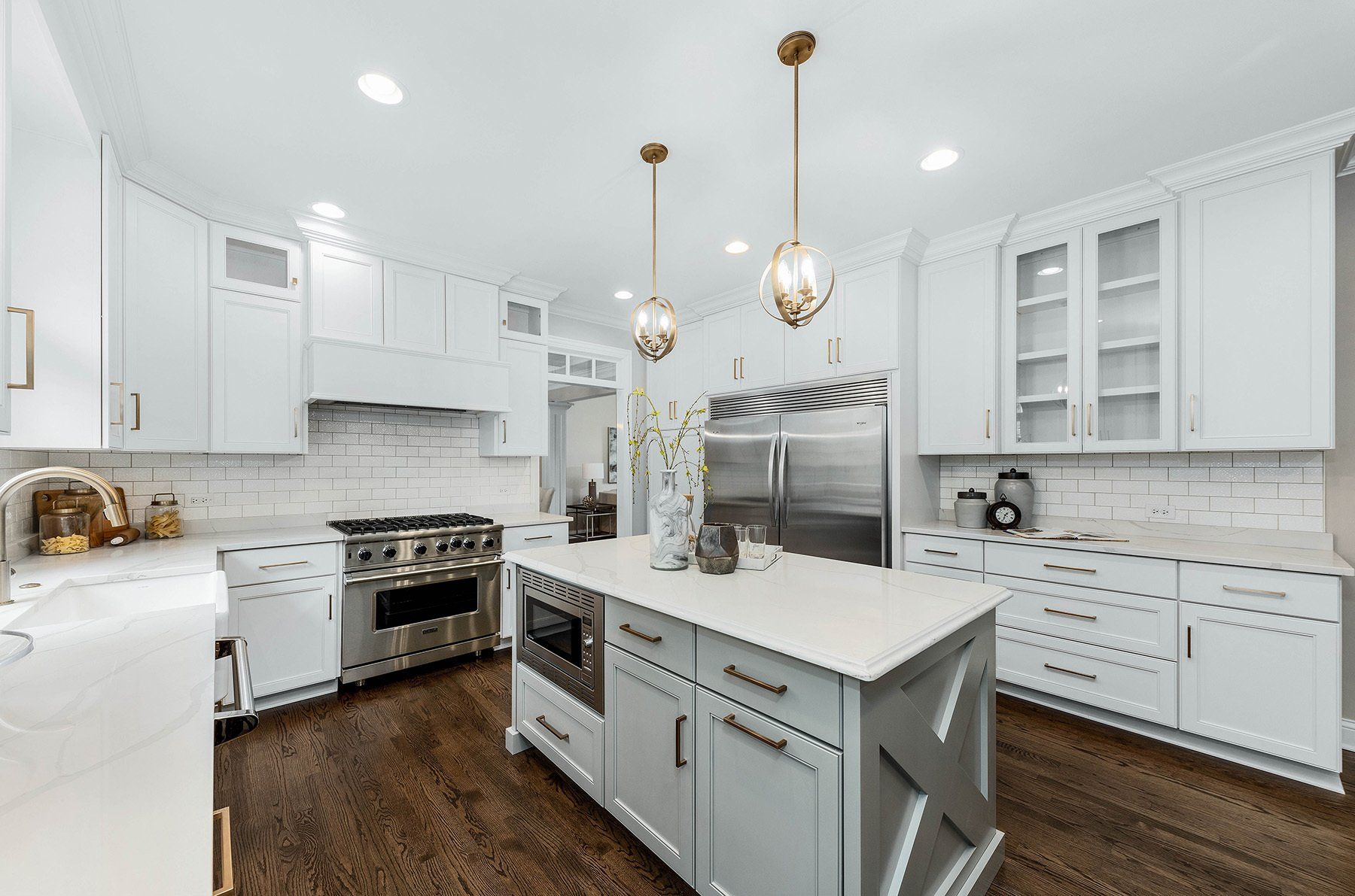 A kitchen with white cabinets , stainless steel appliances , and a large island.