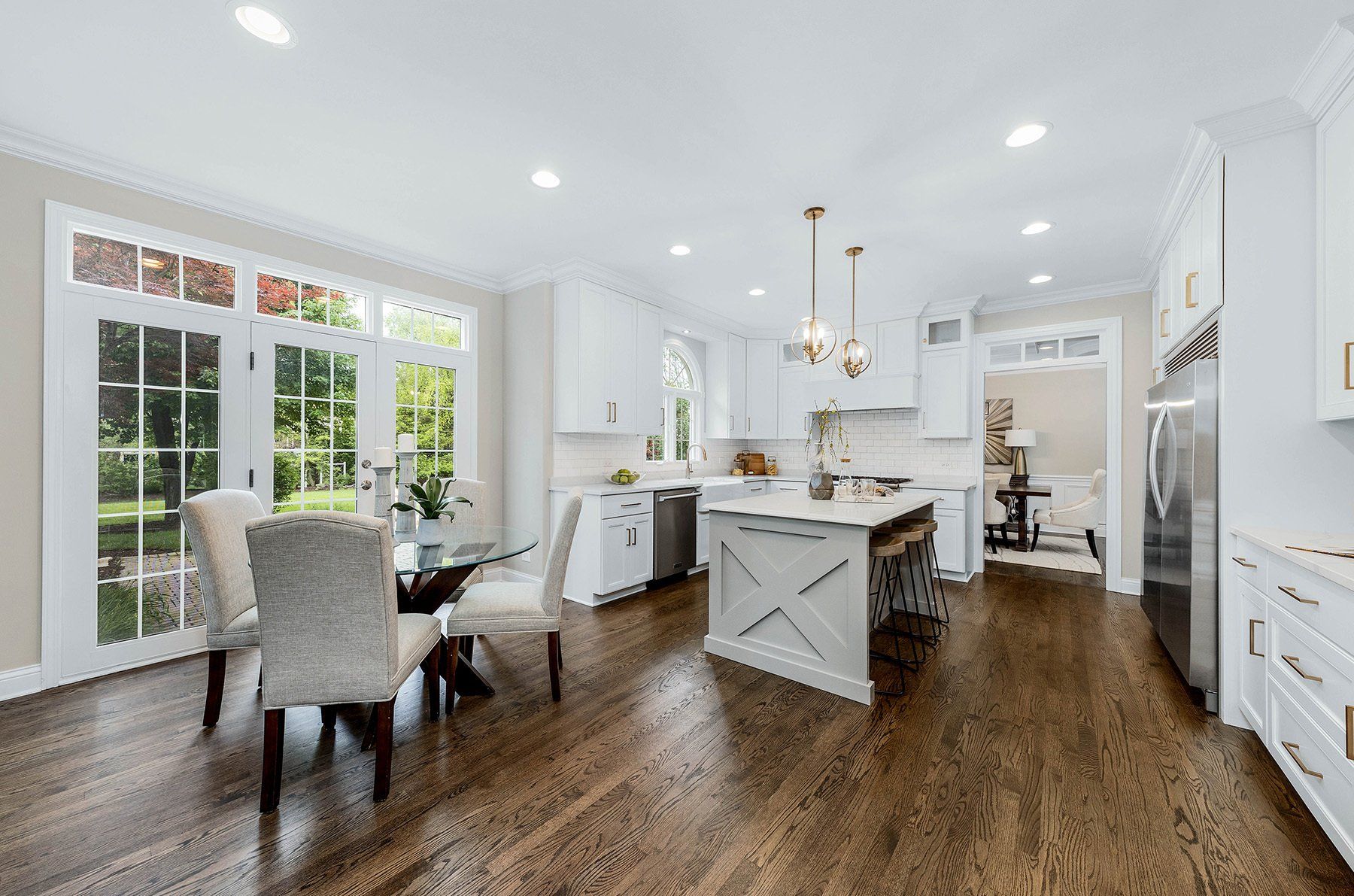 A kitchen and dining room in a house with hardwood floors and white cabinets.