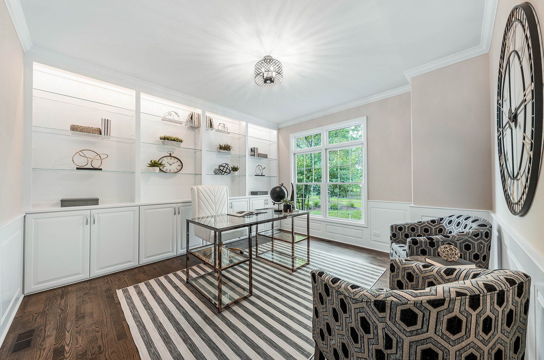 A home office with a desk , chairs , and a striped rug.