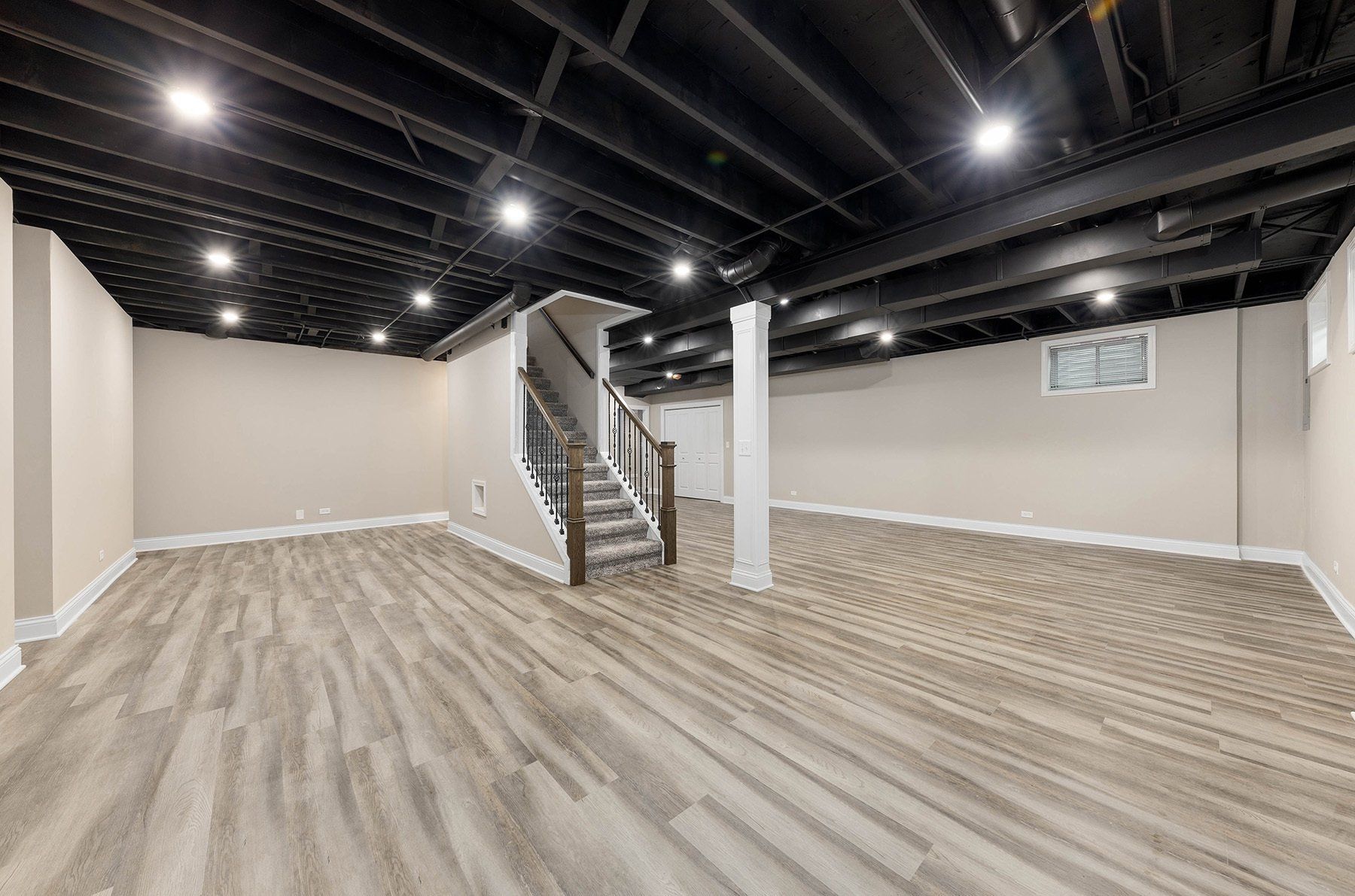 An empty basement with hardwood floors and a black ceiling.