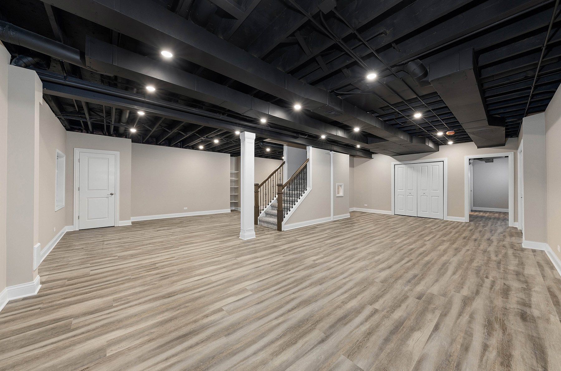 An empty basement with hardwood floors and a staircase.