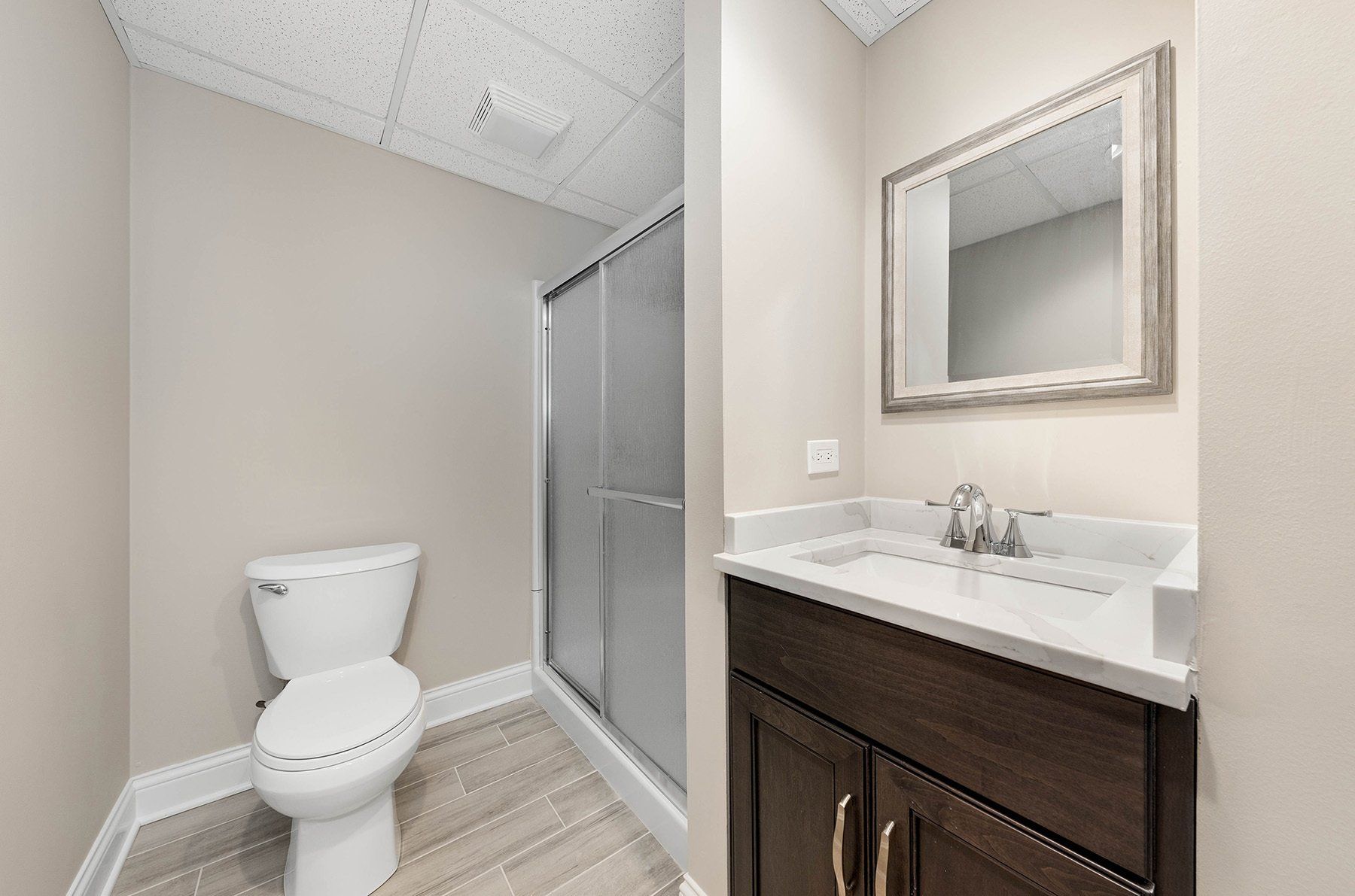 A bathroom with a toilet , sink and mirror.