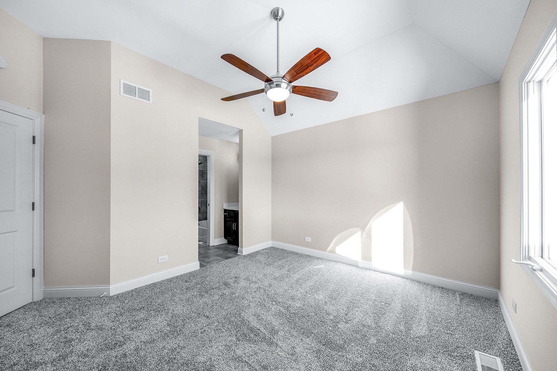 An empty bedroom with a ceiling fan and a window.