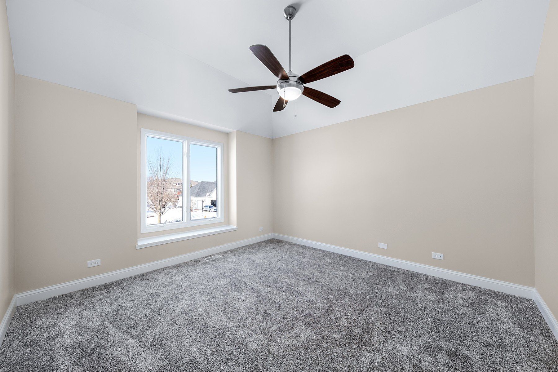 An empty bedroom with a ceiling fan and a window.