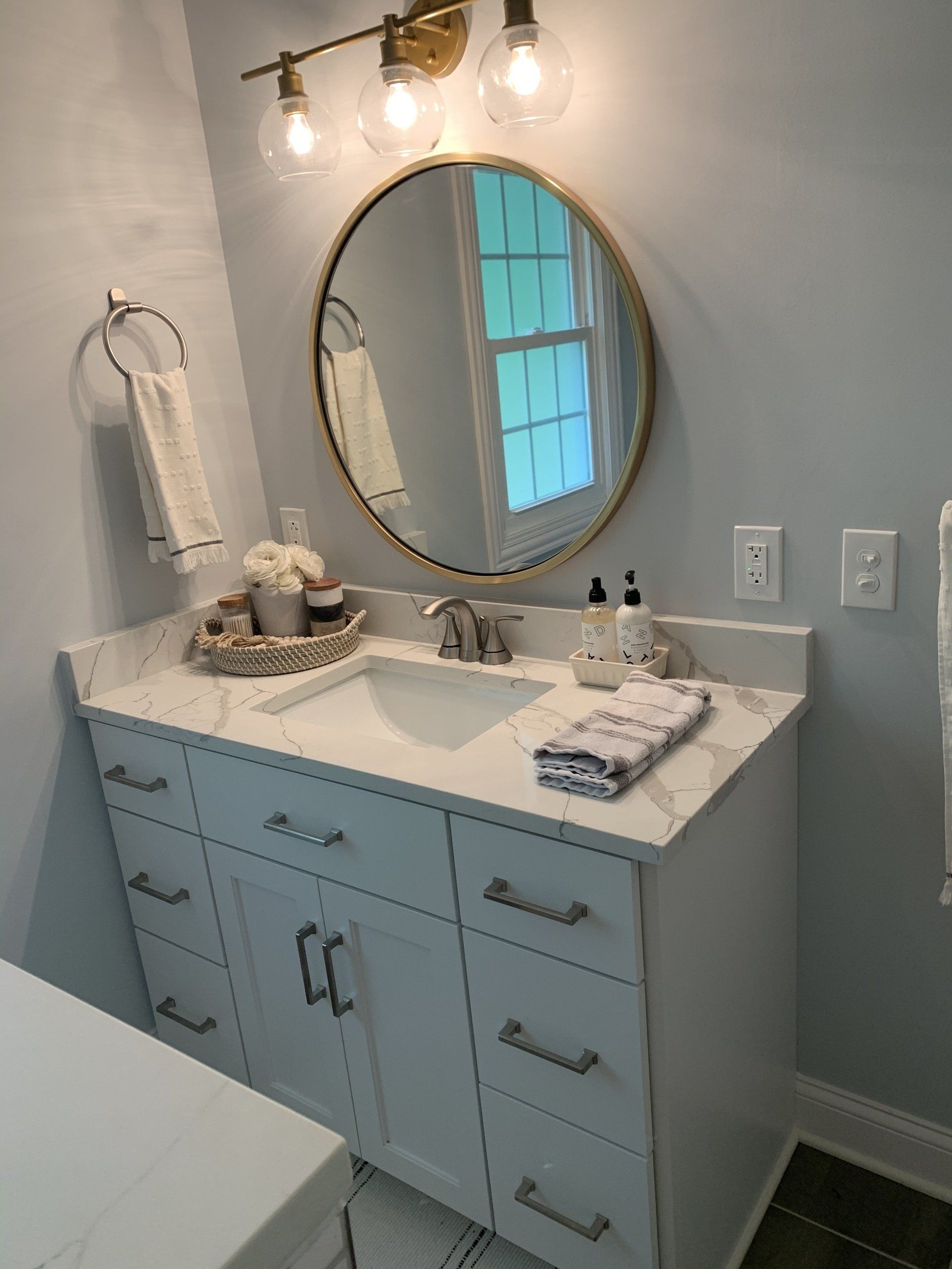 A bathroom with a sink and a round mirror.