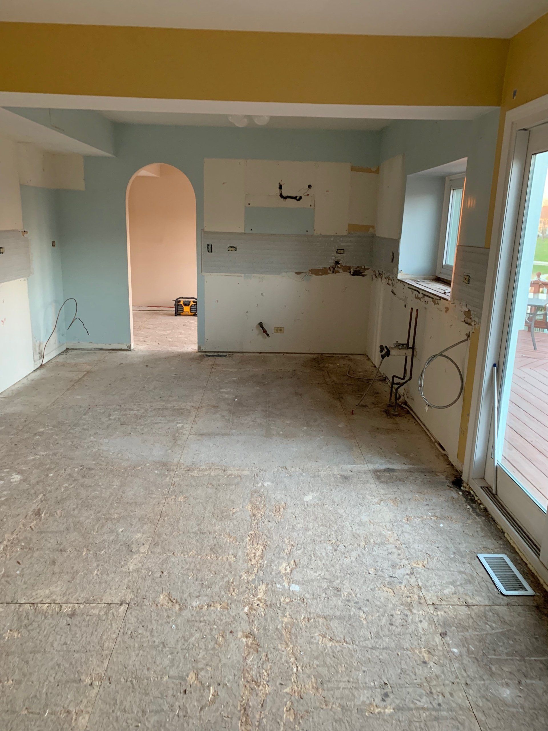 An empty kitchen with a carpeted floor and white cabinets.