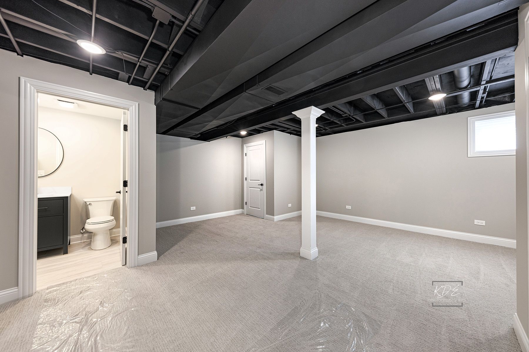 An empty basement with a toilet , sink and mirror.
