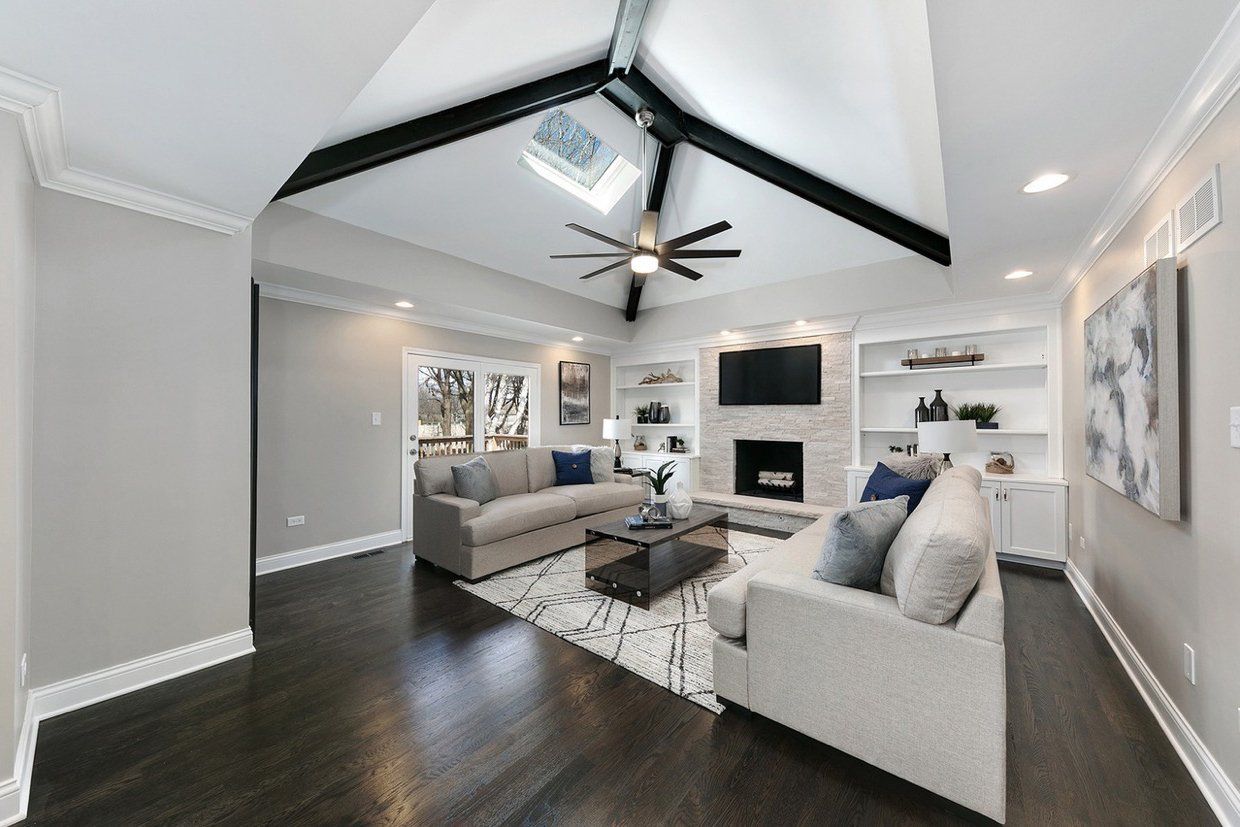 A living room with a couch , fireplace , television and ceiling fan.