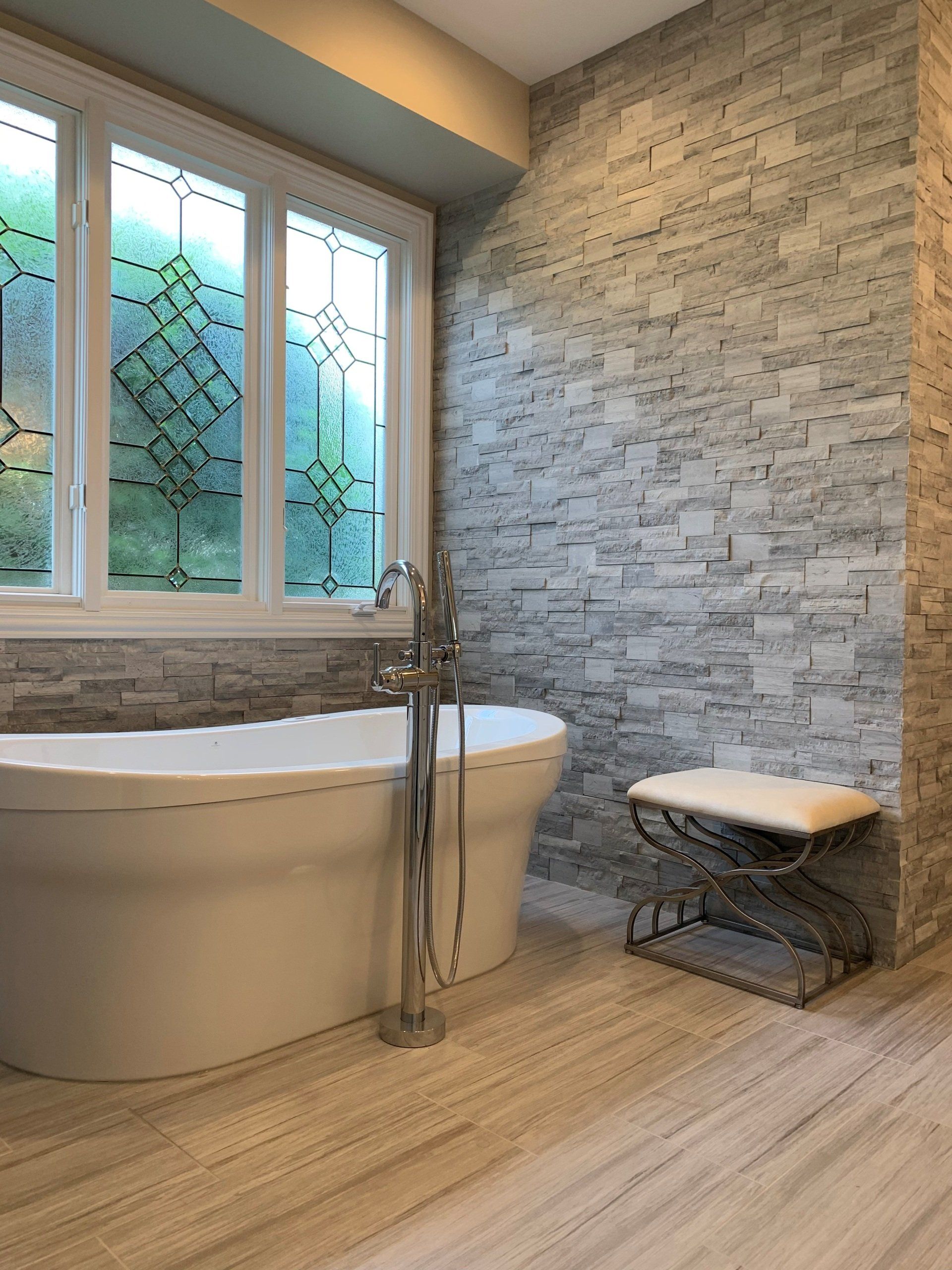 There is a bathtub in the bathroom with a stained glass window.