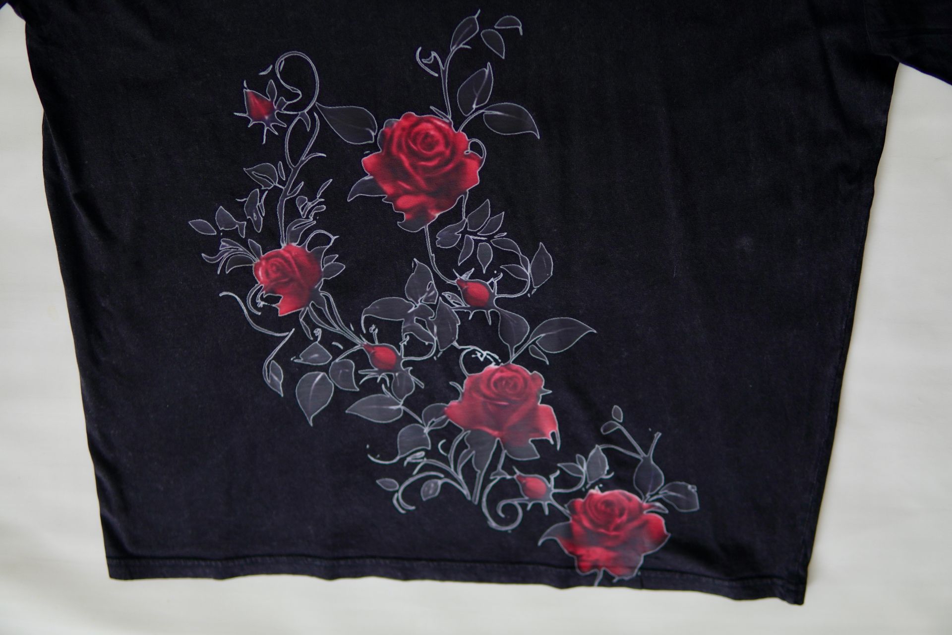 Black t-shirt with a design of red roses and gray vines.