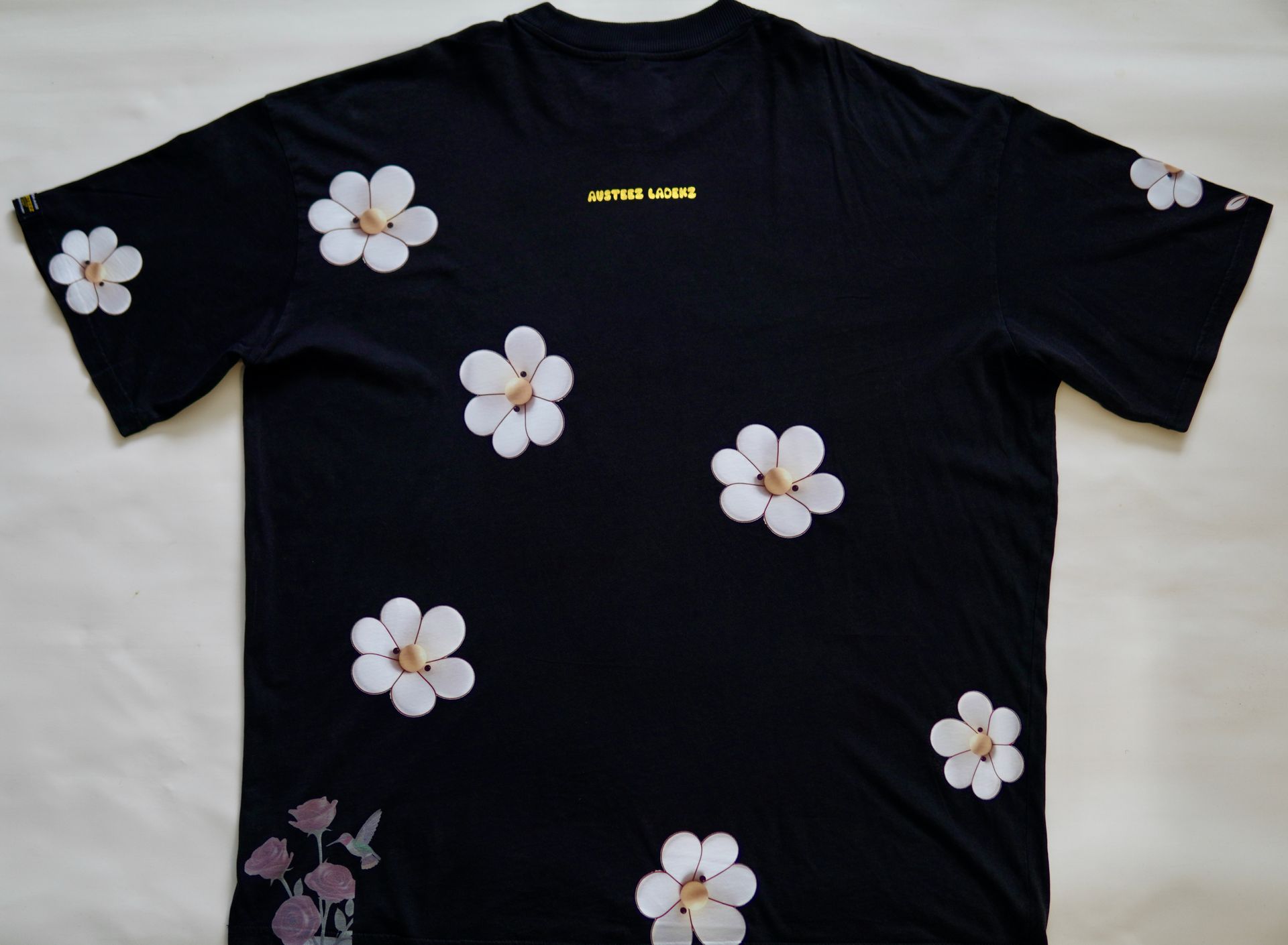Back view of a Black Custom-made with gradient flame-style lettering, 3D rhinestone accents (bling), and soft floral prints on premium cotton. Featuring the Austeez Noble Family woven tag – made for those who live loud but love quiet.
Pre-release drop. Made in limited quantities.