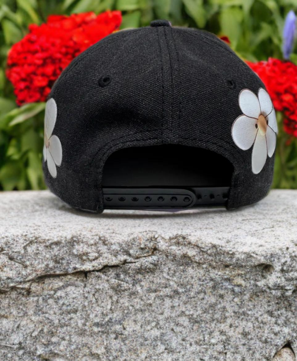 Black and tan baseball cap decorated with white daisies.