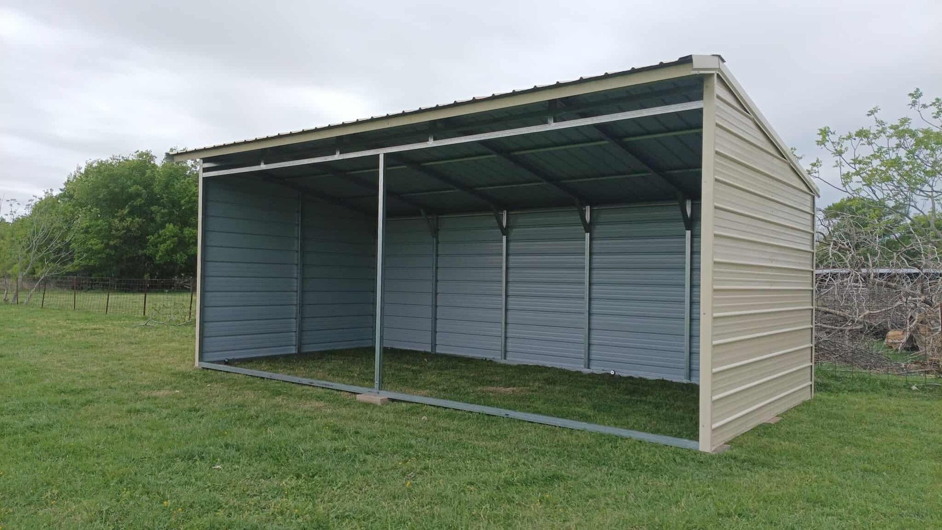 Metal carport shelter in a grassy yard with open sides and a corrugated roof