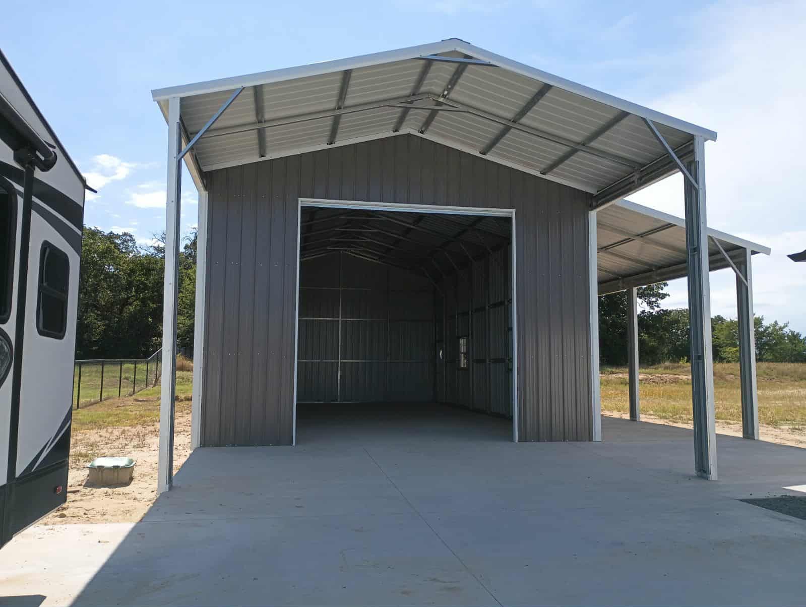 Open-front metal shed with a concrete floor and gray siding in a sunny rural setting