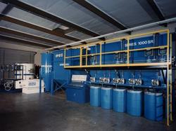 A large blue machine is sitting in a warehouse next to a forklift.