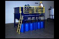 A man is standing on top of a machine with blue barrels.