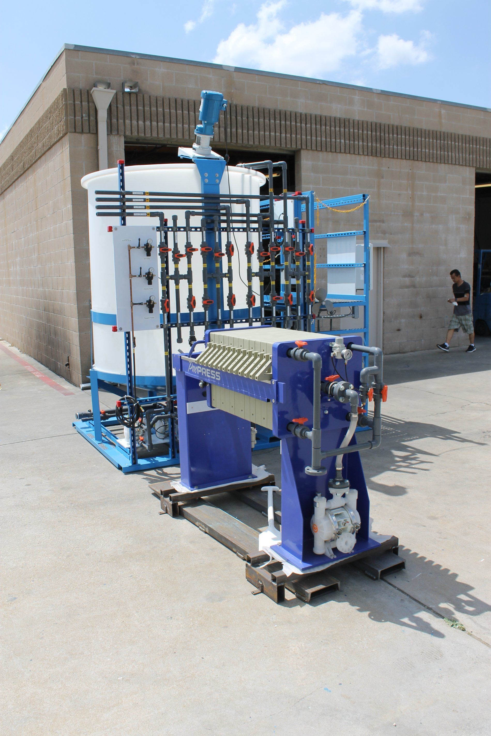 A wastewater treatment machine is sitting on a pallet in front of a building.