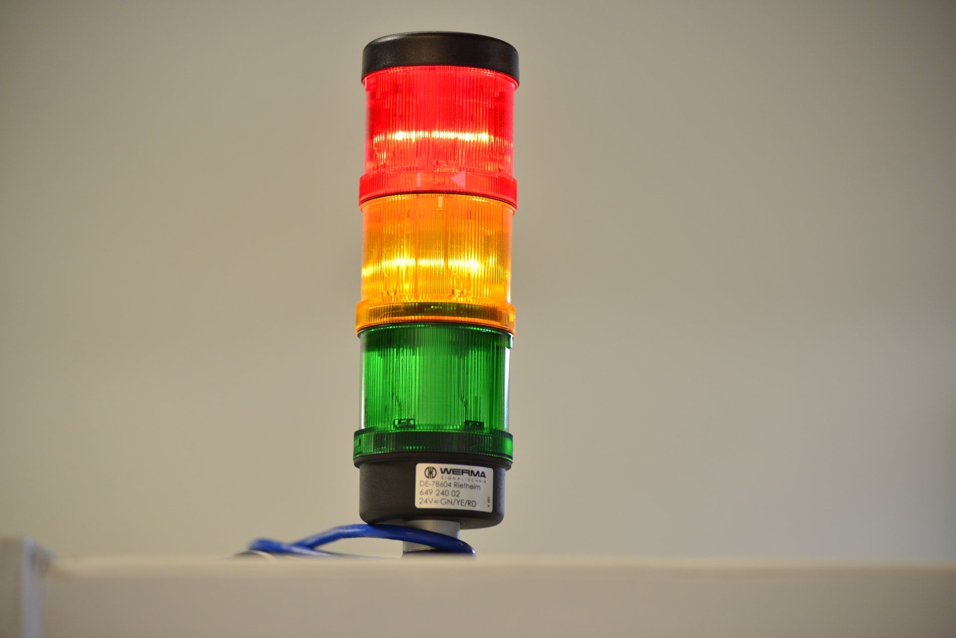 A red , yellow , and green light is stacked on top of each other on a table.
