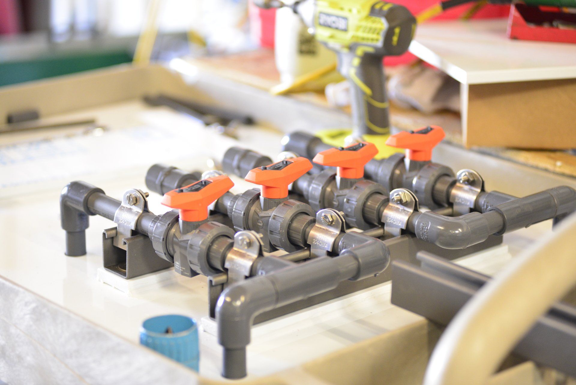 A drill is sitting on a table next to a bunch of pipes.