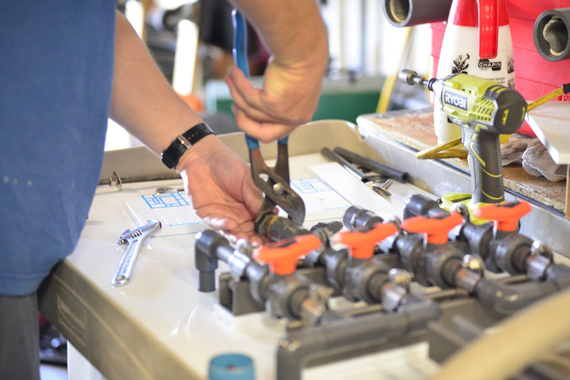 A man is working on a pipe with pliers on a table.