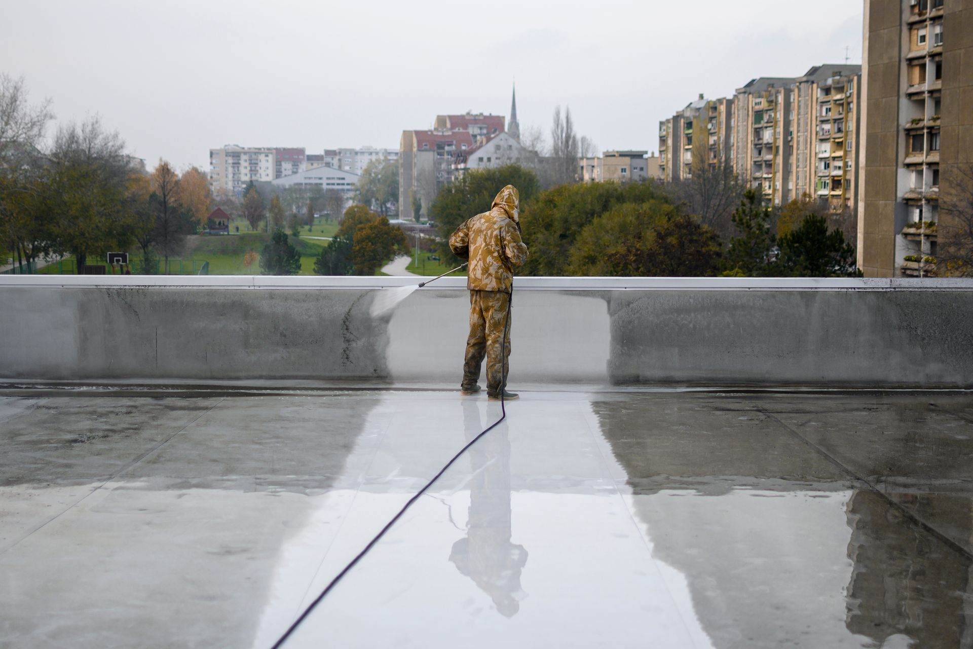 Man in yellow uniform cleaning roof top from dirt. Floor is all under water