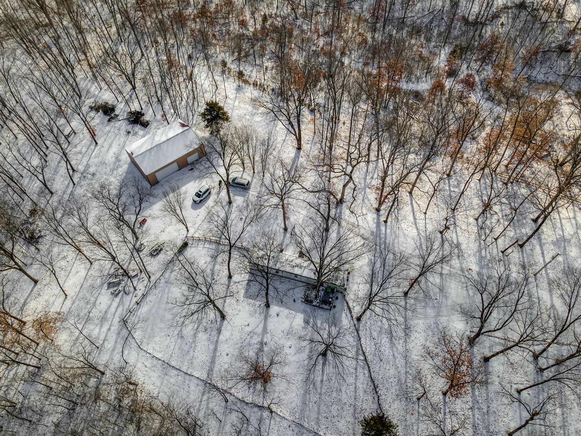 An aerial view of a house in the middle of a snowy forest.