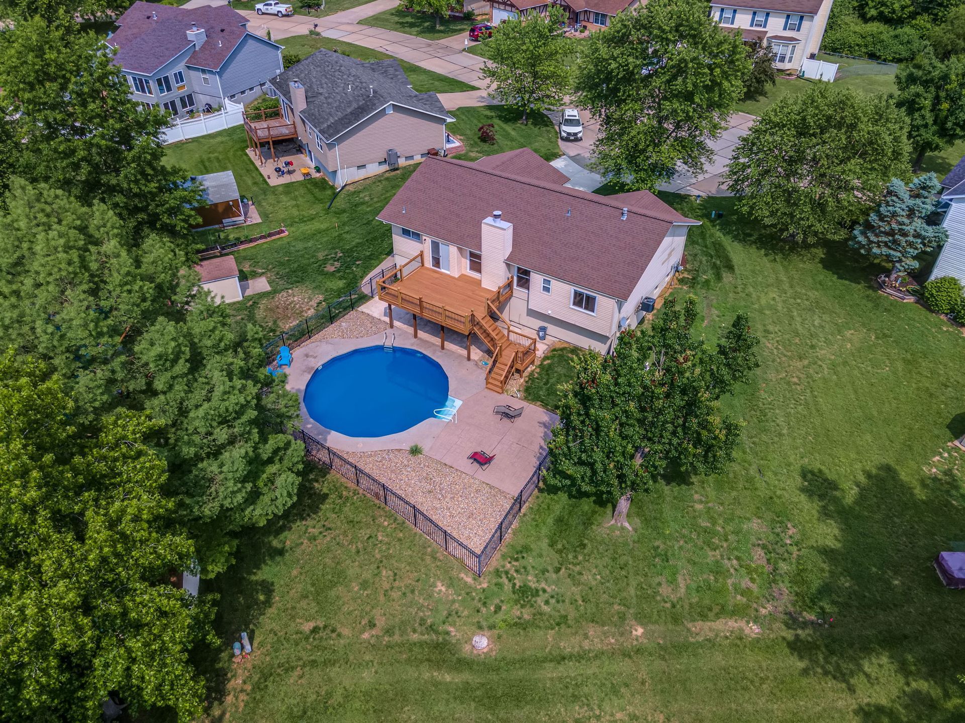 An aerial view of a house with a pool in the backyard surrounded by trees.