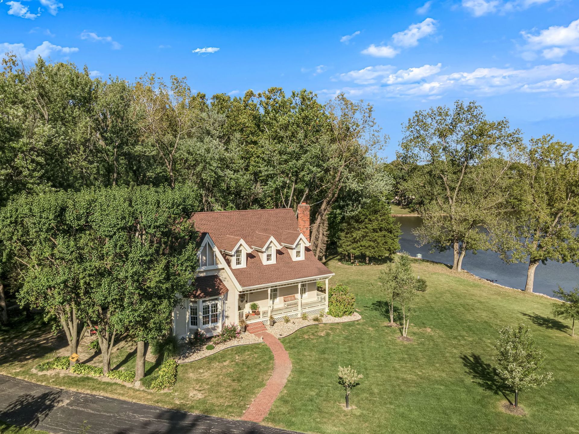 An aerial view of a house surrounded by trees and a lake.