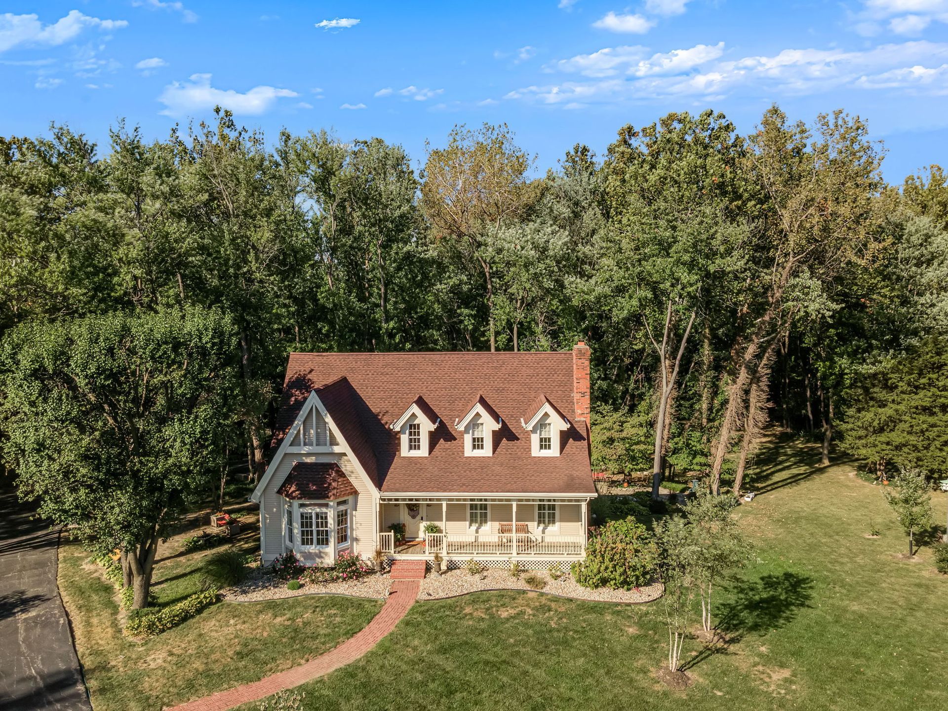 An aerial view of a house surrounded by trees and grass.