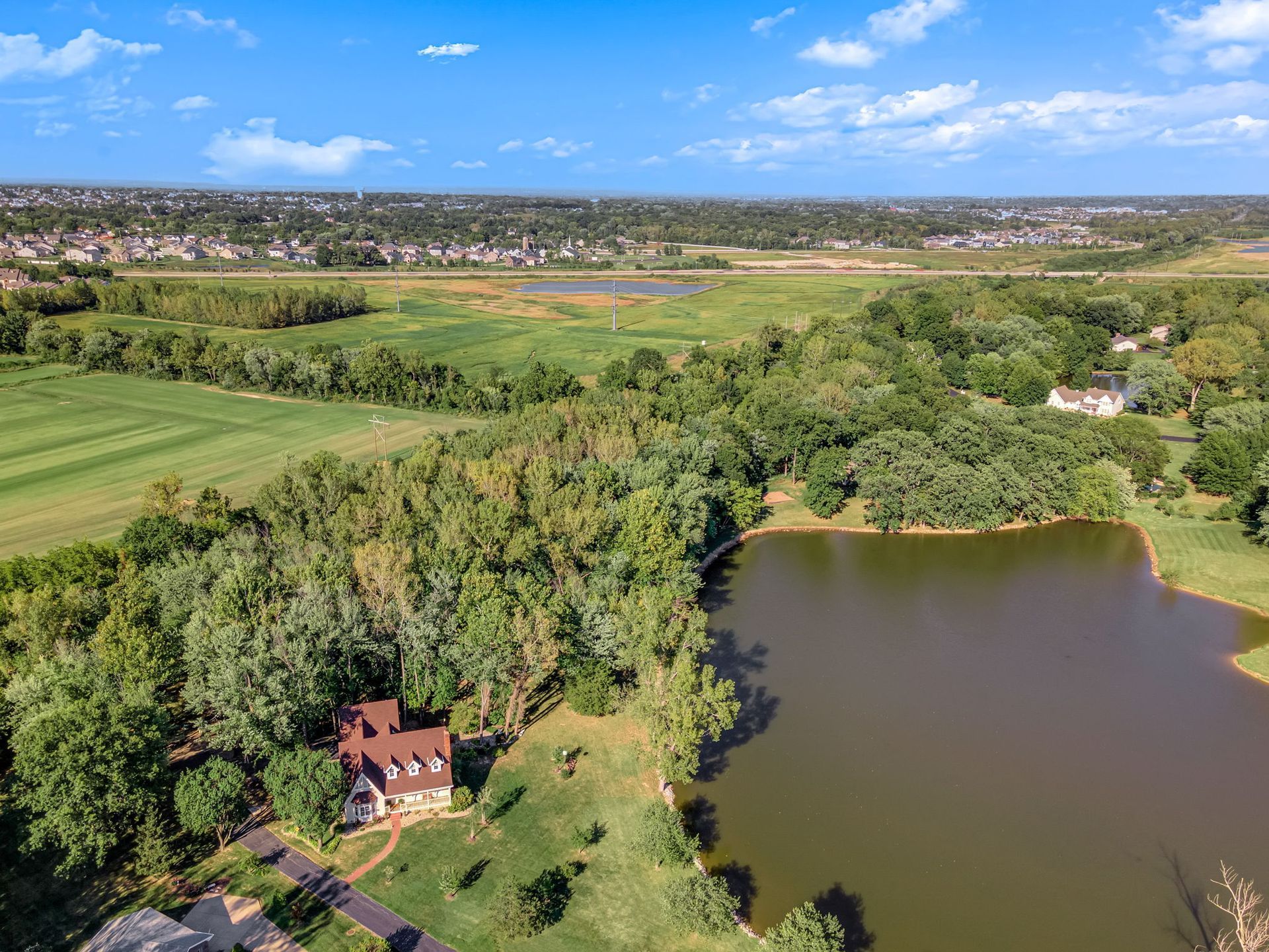 An aerial view of a house next to a lake surrounded by trees.