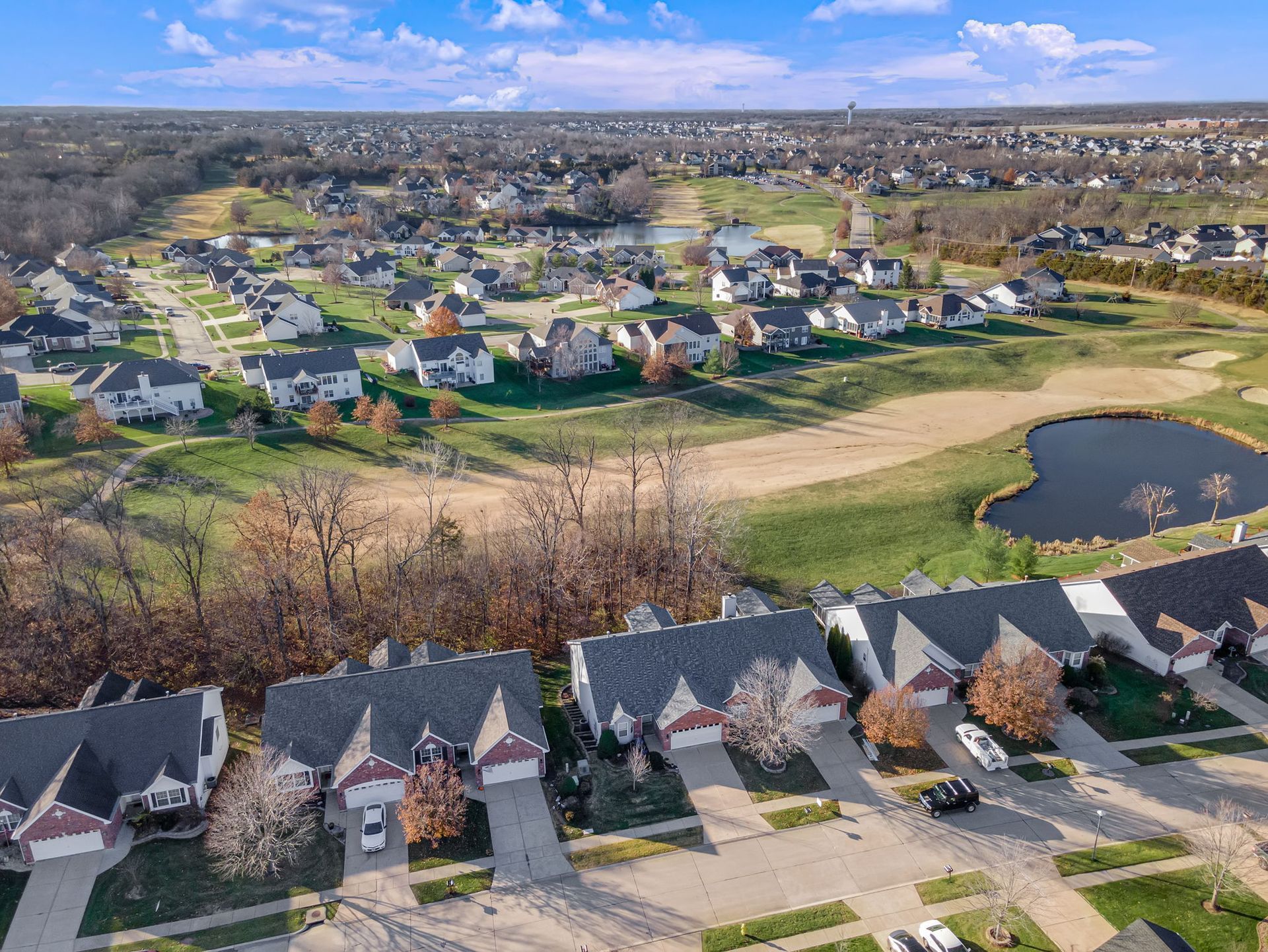 An aerial view of a residential neighborhood with a golf course in the background.