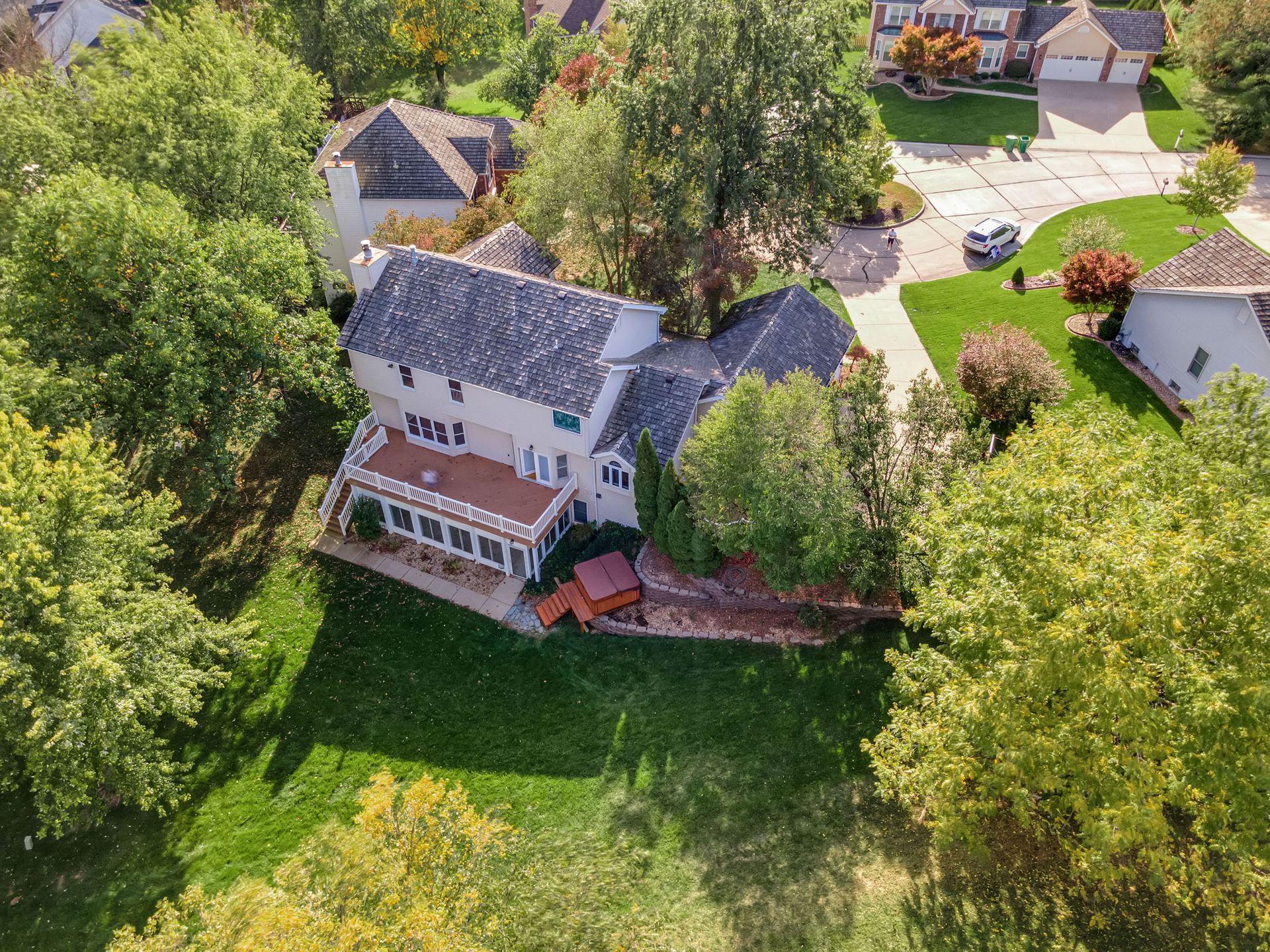 An aerial view of a house in a residential area surrounded by trees.