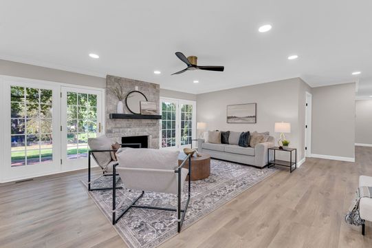 A living room with a couch , chairs , a fireplace and a ceiling fan.