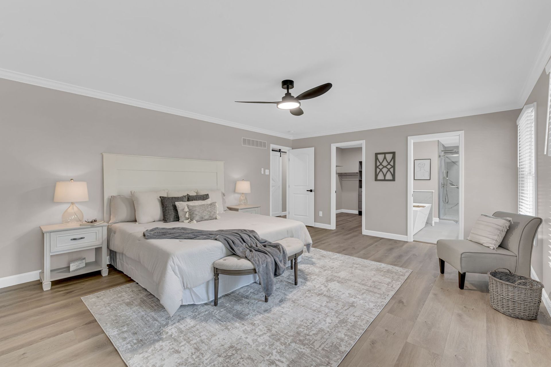 A bedroom with a bed , chair , nightstand and ceiling fan.