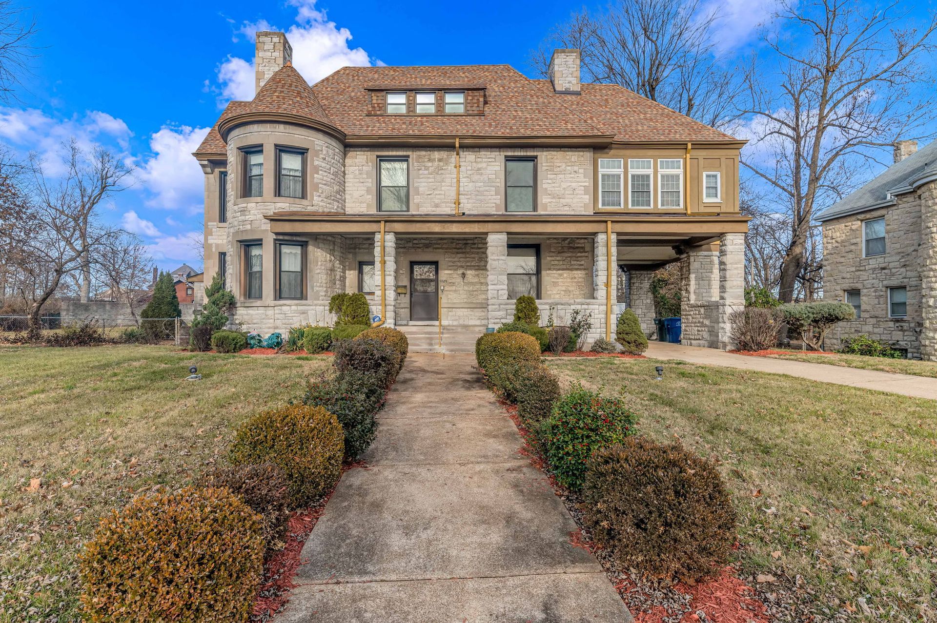 A large stone house with a brick walkway leading to it.