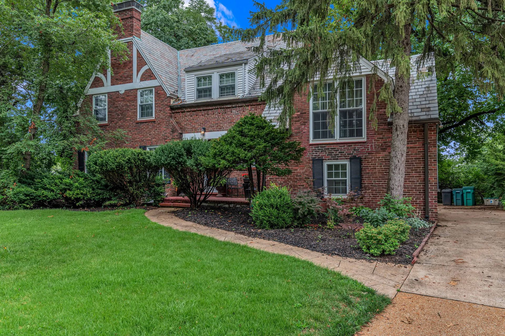 A large brick house with a large lawn in front of it.