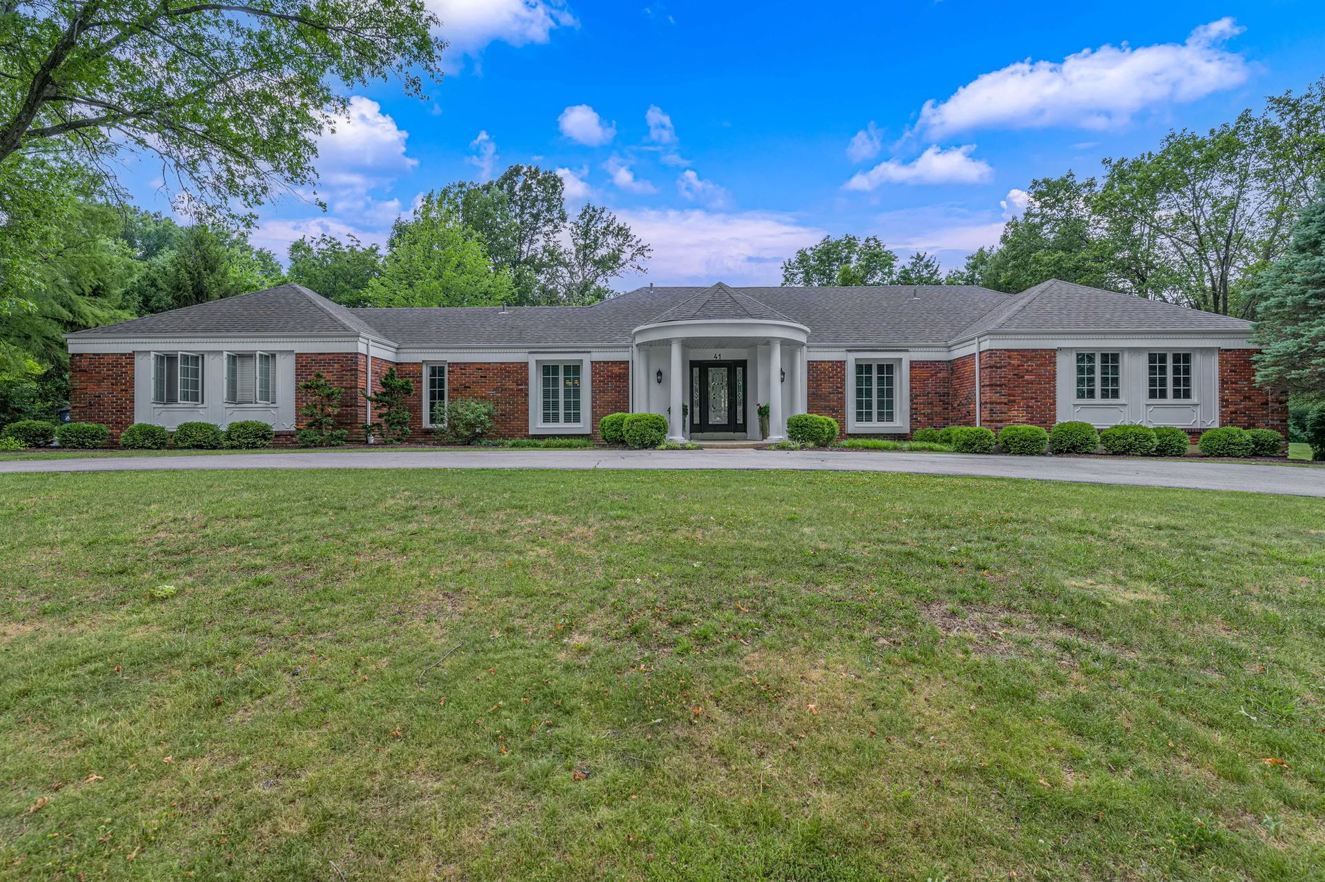 A large brick house with a large lawn in front of it.