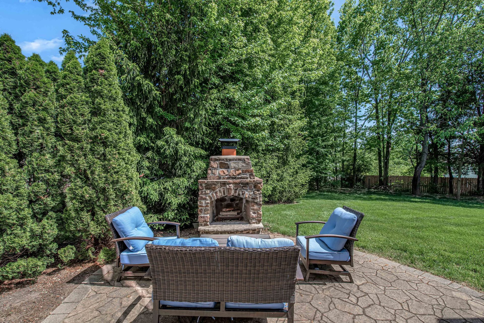 There is a fireplace in the backyard with a couch and chairs.