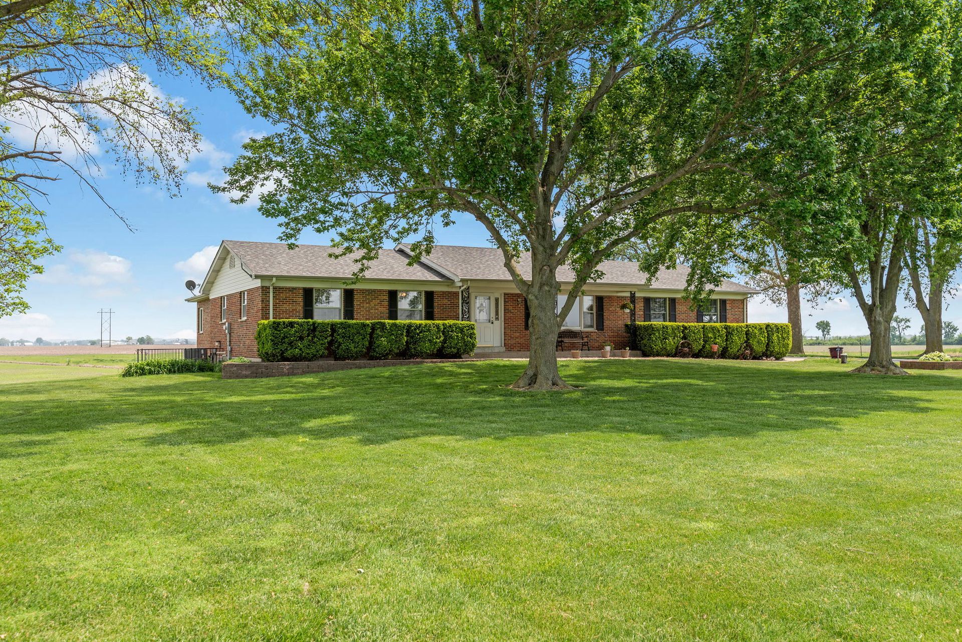 A house is sitting on top of a lush green field surrounded by trees.