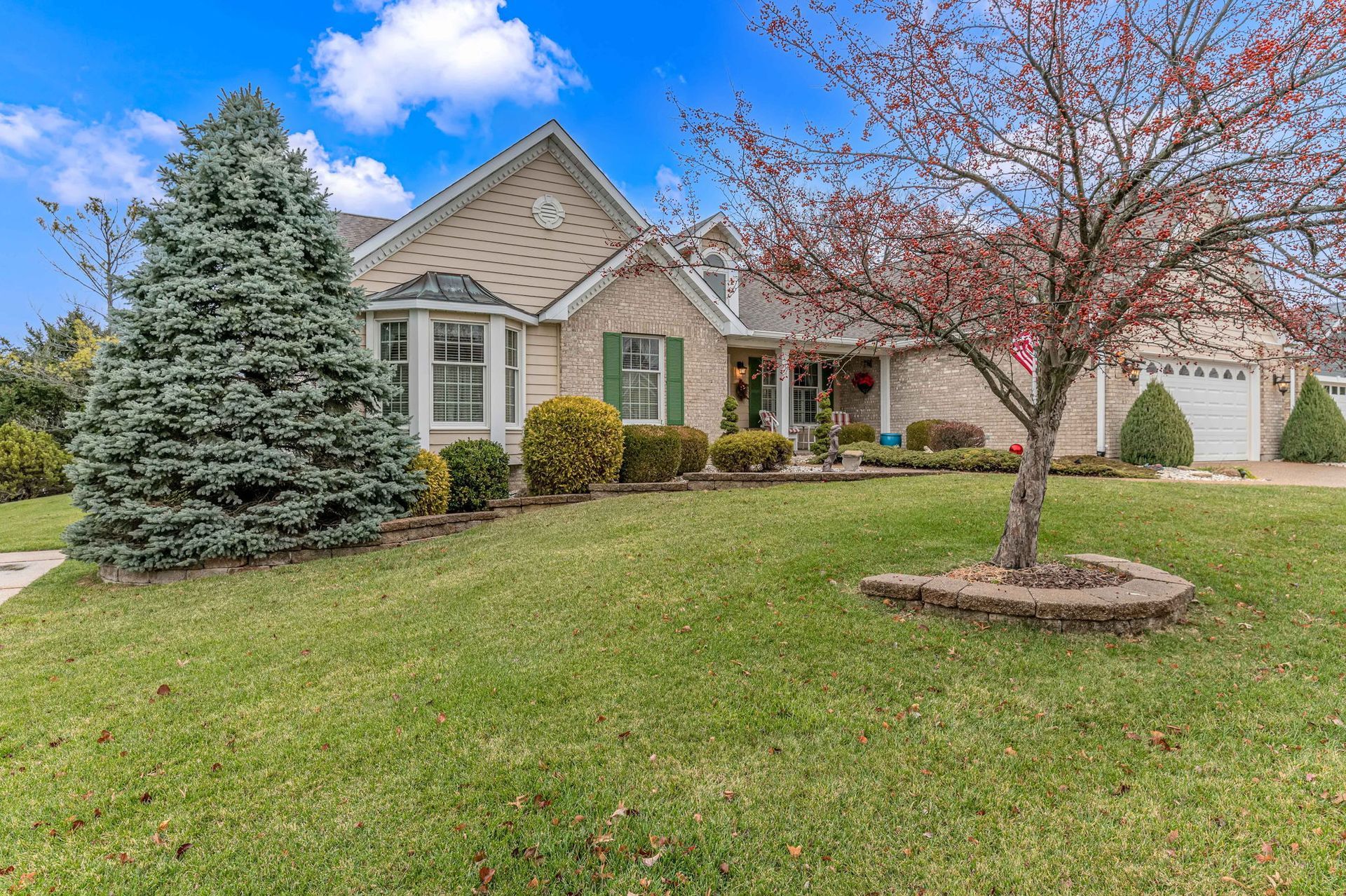 A house with a large lawn and a tree in front of it.