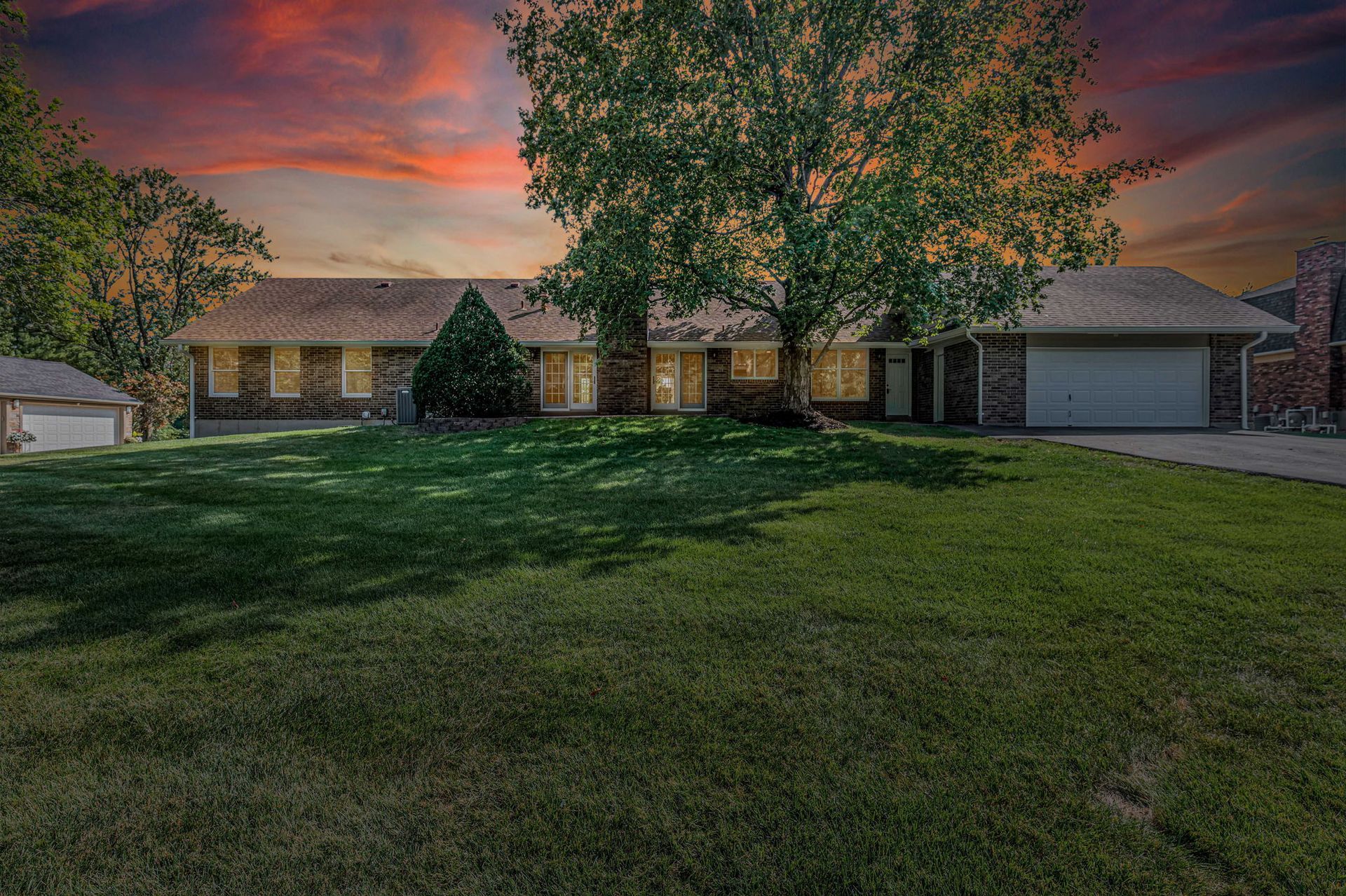 A large house with a large lawn in front of it at sunset.