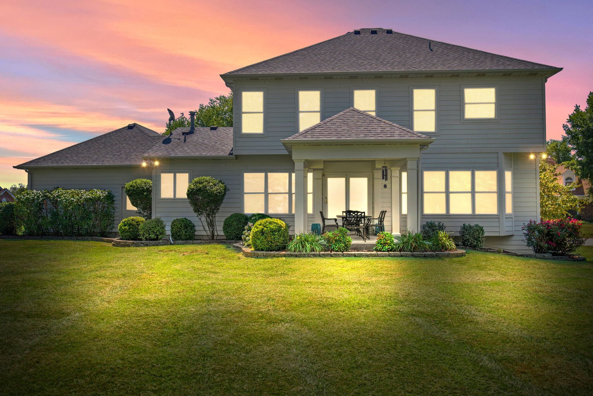 A large white house with a lot of windows is lit up at night.