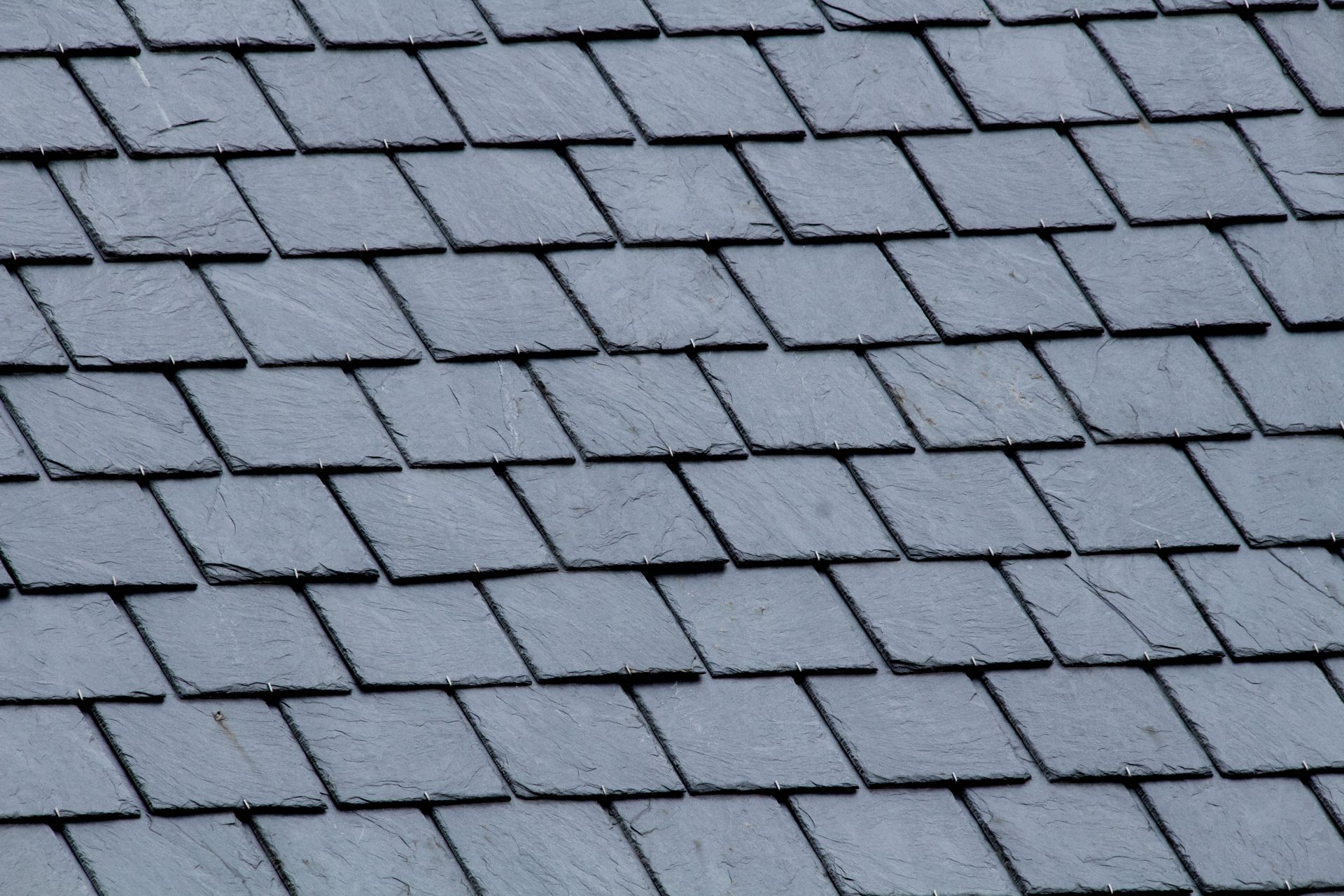 Gray overlapping roof shingles in a close-up pattern