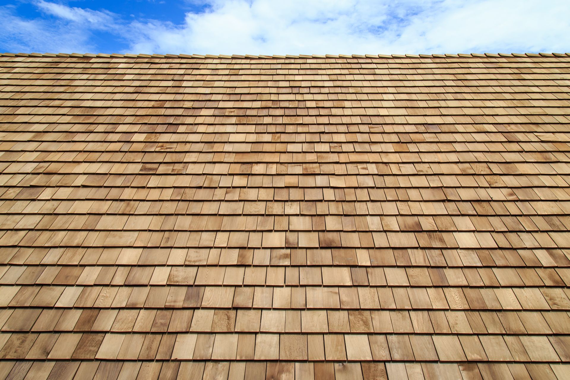 Wooden shingle roof under a blue sky with a few clouds