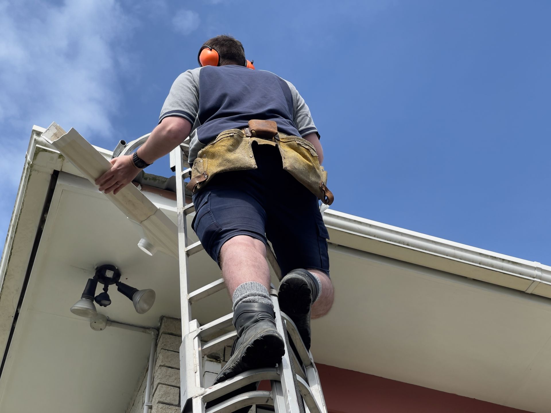 Person on a ladder repairing a sectional gutter.