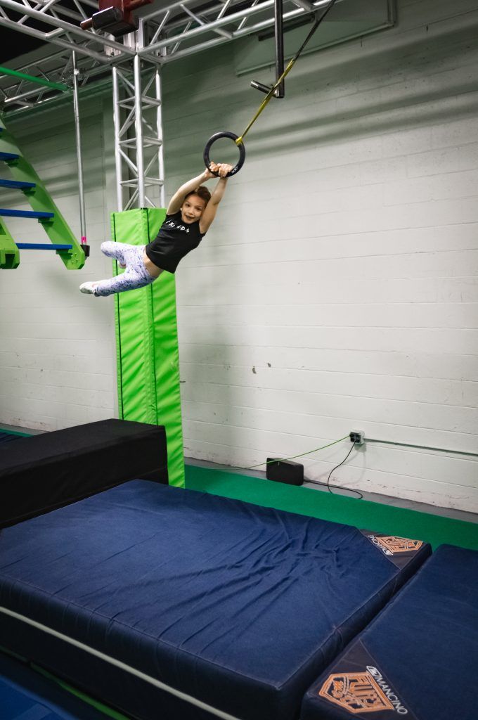 Young girl swinging through obstacle course