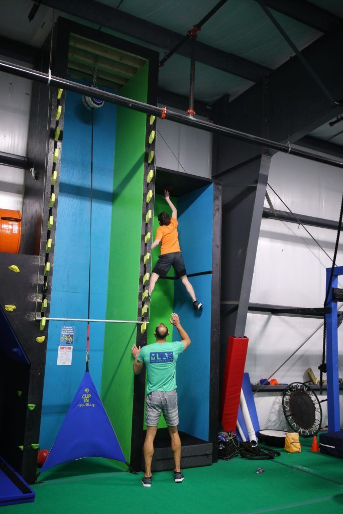 Boy on climbing wall supervised by instructor