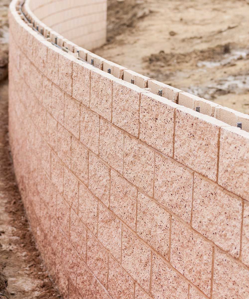 A curved brick wall is being built in the dirt.