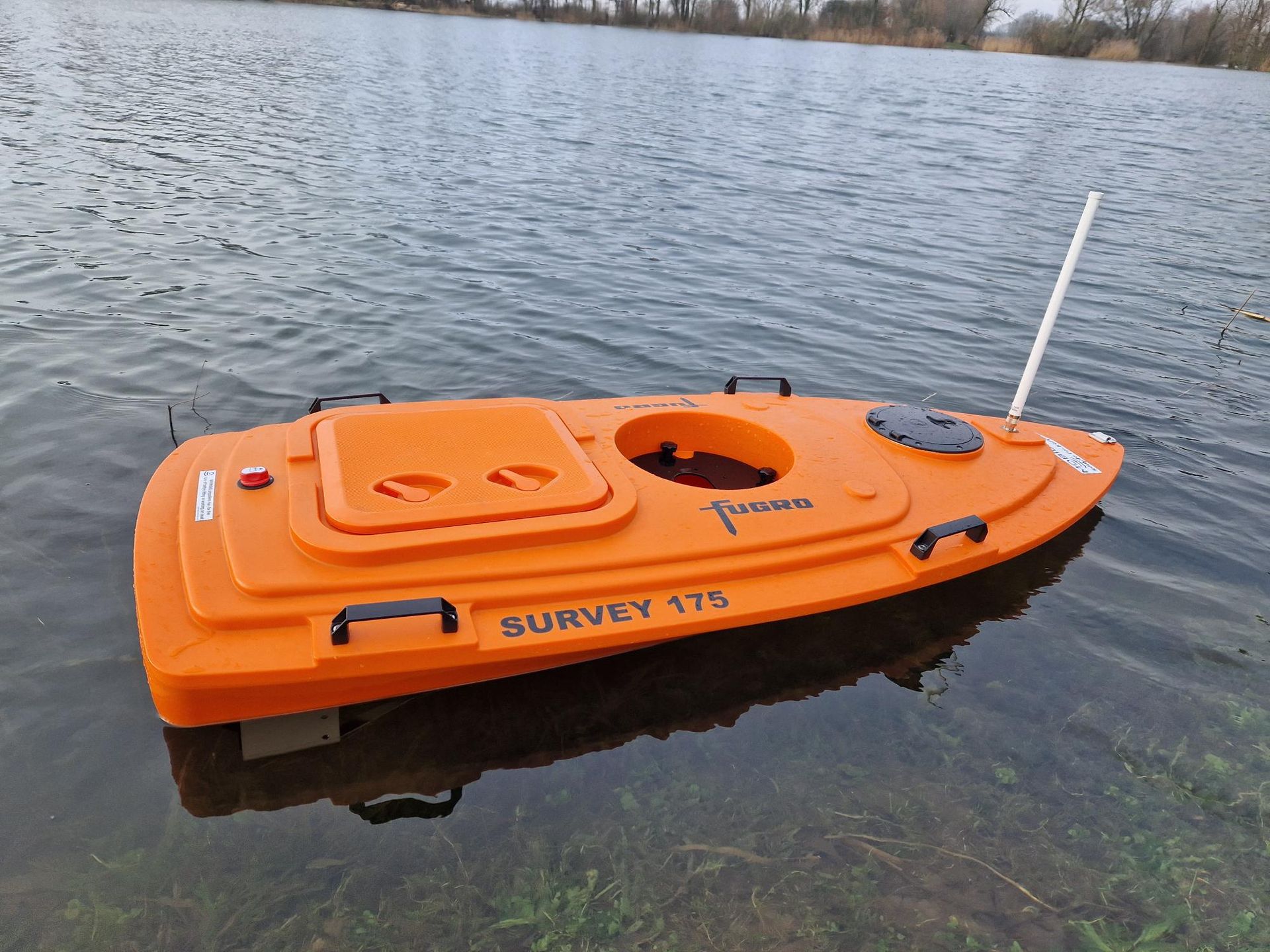 Een kleine oranje boot drijft op een watermassa.