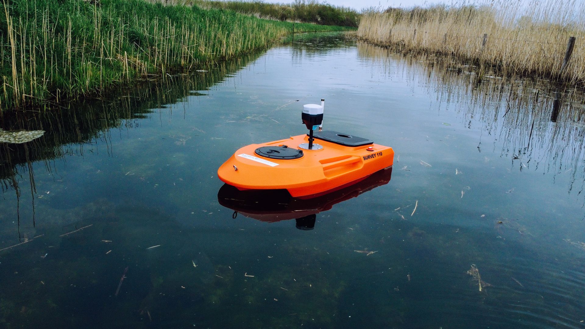 Een kleine oranje boot drijft op een watermassa.